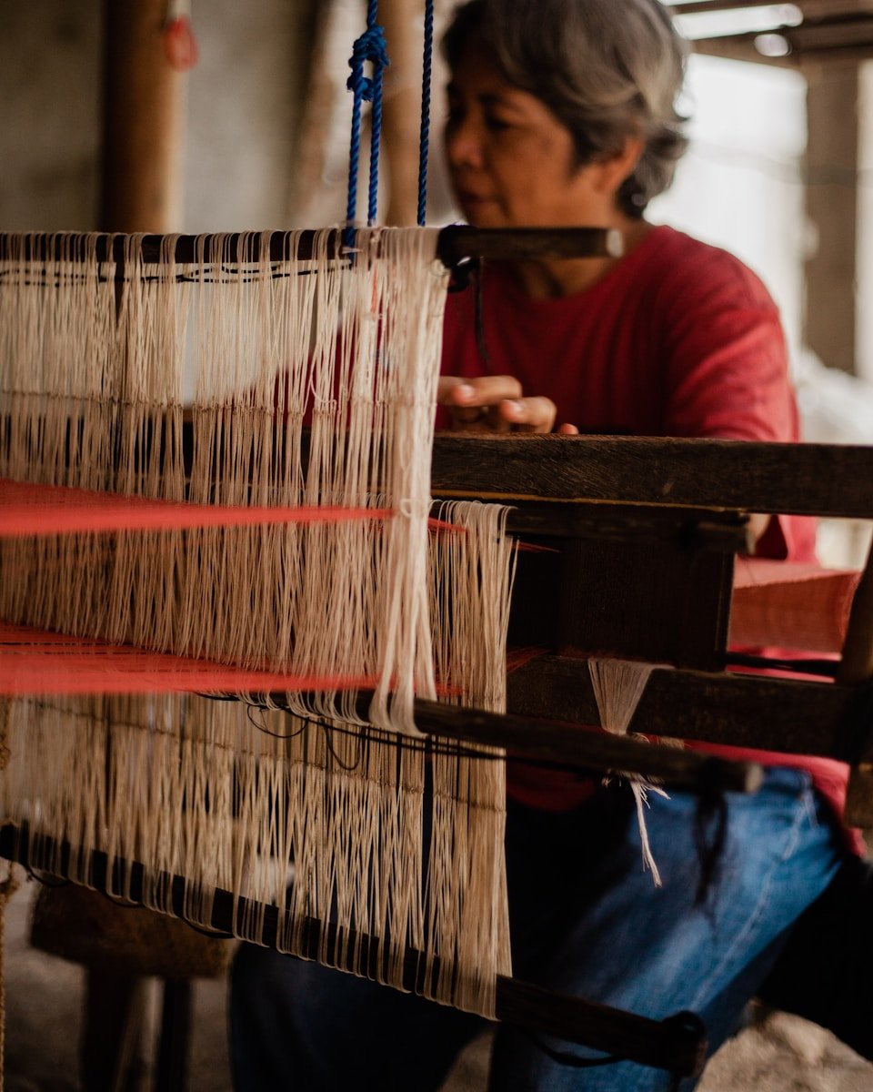 woman in red long sleeve shirt and blue denim jeans sitting on brown wooden chair